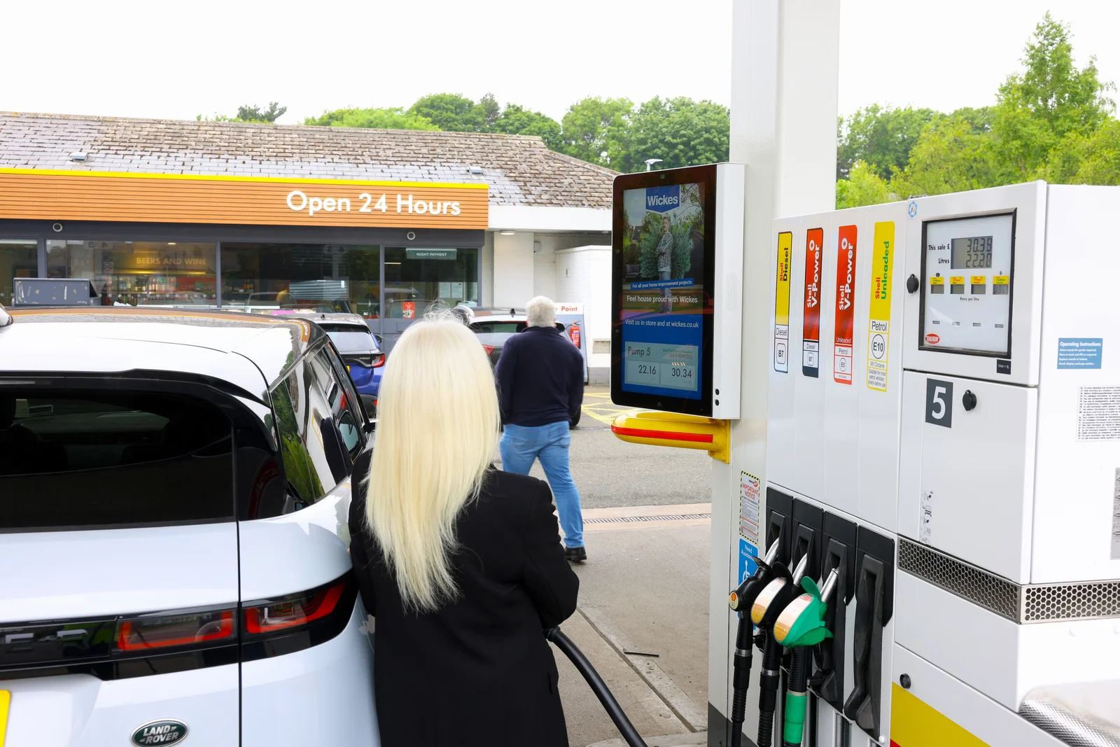 A customer refuels beside a Shell screen
