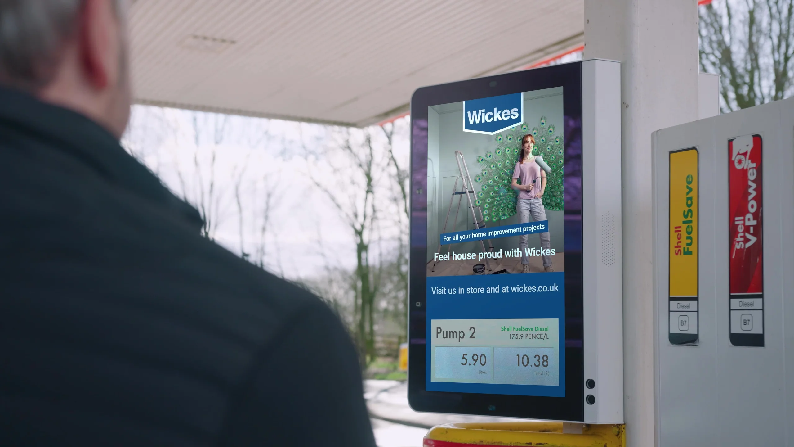 A digital screen beside a Shell fuel pump
